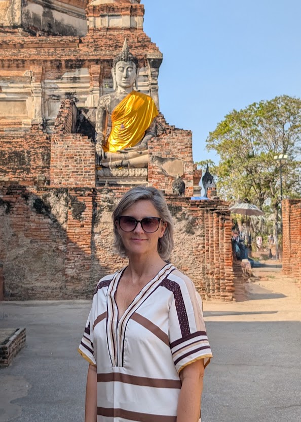 Heidi foran en Buddhafigur mellem gamle murstensruiner